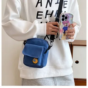 Close-up detail of the stylish blue canvas crossbody bag with front pocket and cute patch.