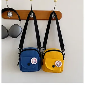 Sac bandoulière en toile vue de détail, accroché au mur avec joli badge lapin, couleurs.