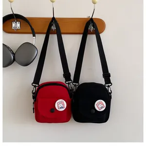 Vue de détail des sacs à bandoulière en toile sur crochet avec badge avant et design compact.