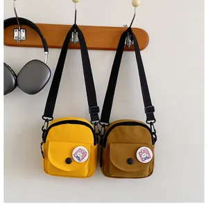 Vue détaillée du petit sac bandoulière en toile avec badge lapin mignon et sangle réglable.