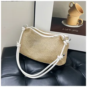 Detail shot of straw woven shoulder bag with white leather strap and zipper closure in cozy scene.