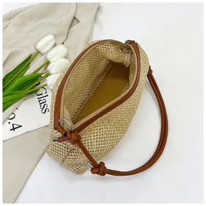 Close-up detail of straw woven underarm bag, showing textured fabric, brown leather trim.