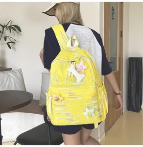 Sac à dos jaune élégant avec de charmants pendentifs en peluche et des motifs colorés pour filles.