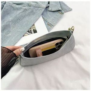 Silver metallic underarm shoulder bag featuring embossed skull pattern and practical pocket details.