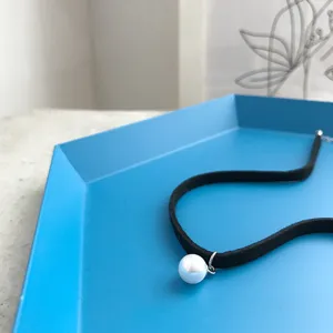 Collana choker in velluto nero con ciondolo di perla singola, primo piano dettagliato donna.