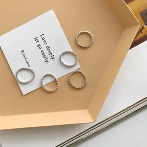 Vista ravvicinata dettagliata di anelli minimalisti in argento sterling con zirconi su un cartoncino.