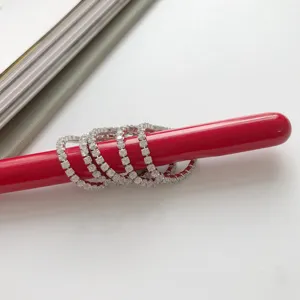 Vista dettagliata di anelli impilabili minimalisti in argento con zirconi su supporto rosso.