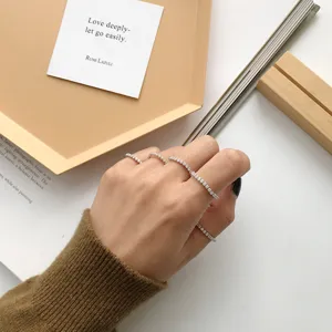 Primo piano dettagliato di anelli minimalisti in argento sterling e zirconi sulle dita.