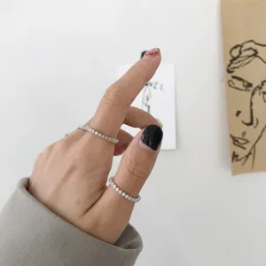 Primo piano di anelli sottili in argento con zirconi splendenti indossati sulla mano.