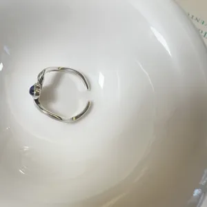 Gros plan détaillé de la bague ouverte en argent vintage avec un design de vagues unique.