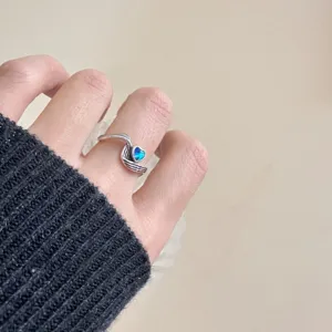 Gros plan sur la bague cœur en argent rétro avec détail de cristal bleu, style vintage.