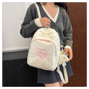 Detail shot of a white plush backpack featuring cute pink heart embroidery and soft texture.