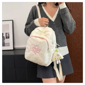 Detailed view of the cute white plush backpack with pink heart embroidery and soft texture.