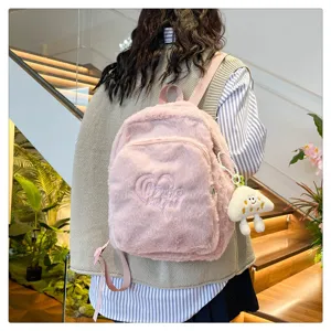 Cute pink plush backpack detail showing soft furry texture, heart embroidery and charm.
