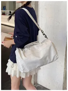 Sac de voyage blanc élégant avec bandoulière, idéal pour les week-ends et le sport.