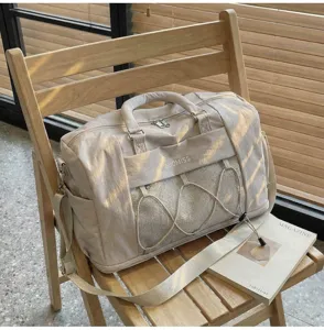 Detailed view of beige travel duffel gym bag with mesh pocket and adjustable shoulder strap.