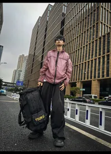 Outdoor street style detail view showing a large multi-functional black travel duffel bag.