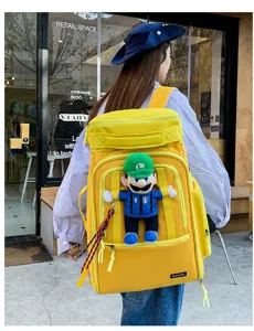 Detail view of large yellow travel backpack featuring cute plush pendant and durable straps.