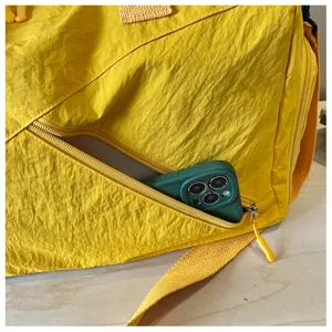 Primer plano detallado de una bolsa de viaje amarilla brillante con bolsillo frontal con cremallera.