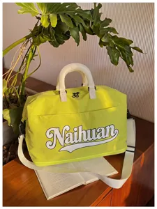 Vista detallada de la elegante bolsa de viaje verde lima con asas blancas y letras.