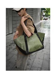 Detail view of the large green canvas tote bag with black trim and handles for travel commuting.