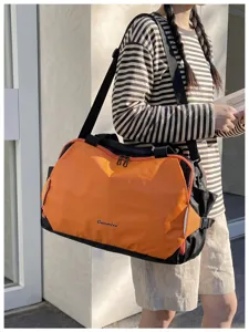 Close-up detail of the stylish color-blocked travel duffel bag in orange and black.