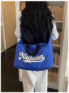 Vista detallada de la bolsa de viaje azul con letras blancas y correa de hombro cómoda.