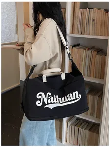 Vista detallada de una bolsa de viaje negra con letras blancas, elegante bolsa de trabajo.