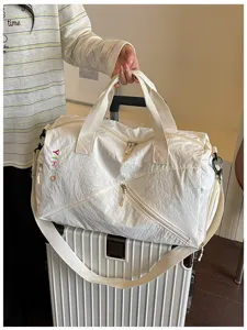 Vista detallada de bolsa de viaje blanca con asas resistentes y bolsillos con cremallera.