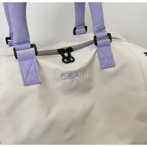 Duffel bag detail showing light purple handles, dual zippers, and embroidered logo text.