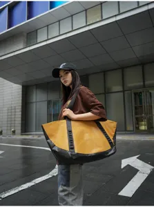 Detailed close-up shot of large color-block travel duffel bag in urban street background.