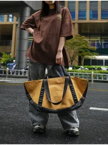 Detail view of large capacity outdoor travel tote bag in yellow and black, durable canvas.
