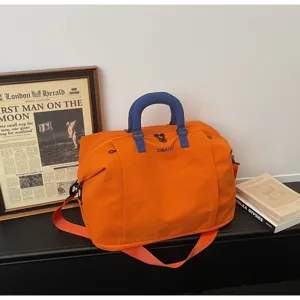 Close-up of orange travel duffel bag, blue handles, durable fabric, convenient luggage detail view.
