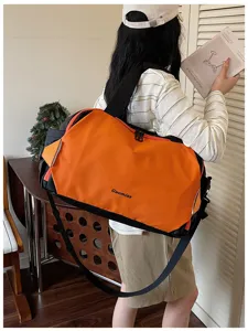 Detailed view of the color-blocking travel duffel bag showcasing stylish orange and black design.
