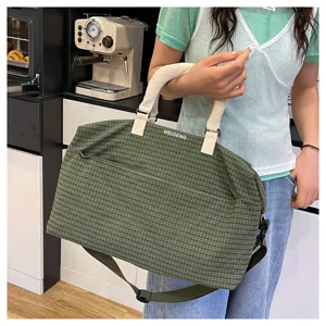 Detail view of the green plaid travel duffel bag featuring sturdy handles and strap.