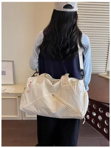 Vista detallada de una bolsa de viaje casual de color liso con correa para deporte.