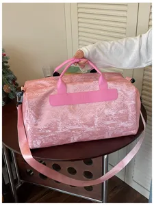 Détail du sac de voyage rose, montrant un tissu texturé de qualité et des poignées.
