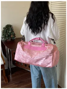 Détail de sac de voyage rose brillant avec bandoulière et poignées pour le sport et trajet.