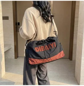 Detailed view of large capacity travel duffel bag with fuzzy letter embroidery and shoulder strap.