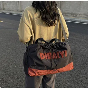 Detailed view of the stylish travel duffel bag with shoulder strap and fuzzy letter patch.