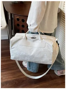Détail de sac de voyage blanc avec texture durable, poignées solides et sangle pour le trajet.