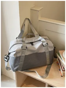 Detailansicht einer grauen Reisetasche mit Schultergurt auf einem Holzregal platziert.