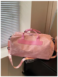 Vue détaillée du sac de voyage rose montrant un tissu texturé et des poignées robustes.