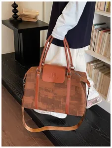 Detail view of stylish brown oil painting travel duffel bag with shoulder strap in cozy room.