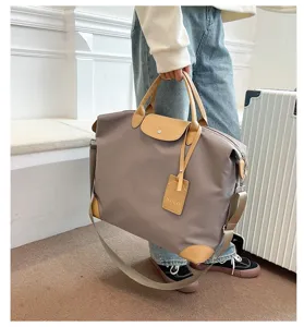 Large capacity waterproof travel duffel bag with leather trim and adjustable strap detail.