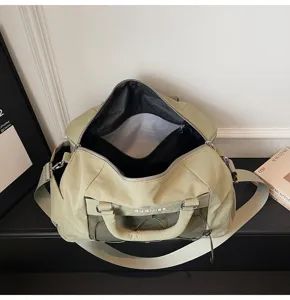 Close view of light green travel duffel bag featuring a large open main compartment and pocket.