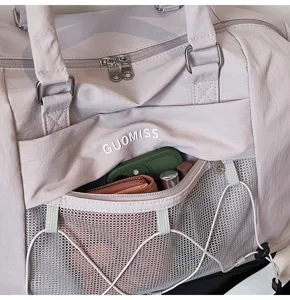 Close-up detail of light grey travel duffel bag with front mesh pocket and adjustable drawstrings.