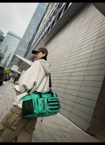 Green gym duffel bag detail, multi-pocket travel sports bag with shoulder strap.