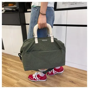 Detailed view of the green plaid travel duffel bag with white handle and shoulder strap.