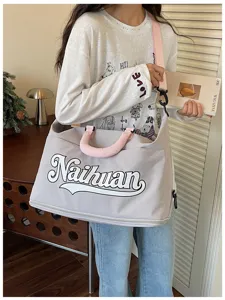 Vista detallada de un elegante bolso de viaje gris con asas rosas y letras impresas.
